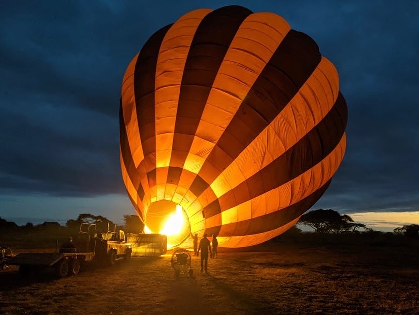Hot air balloon being inflated at sunrise with Mount Kilimanjaro in the background